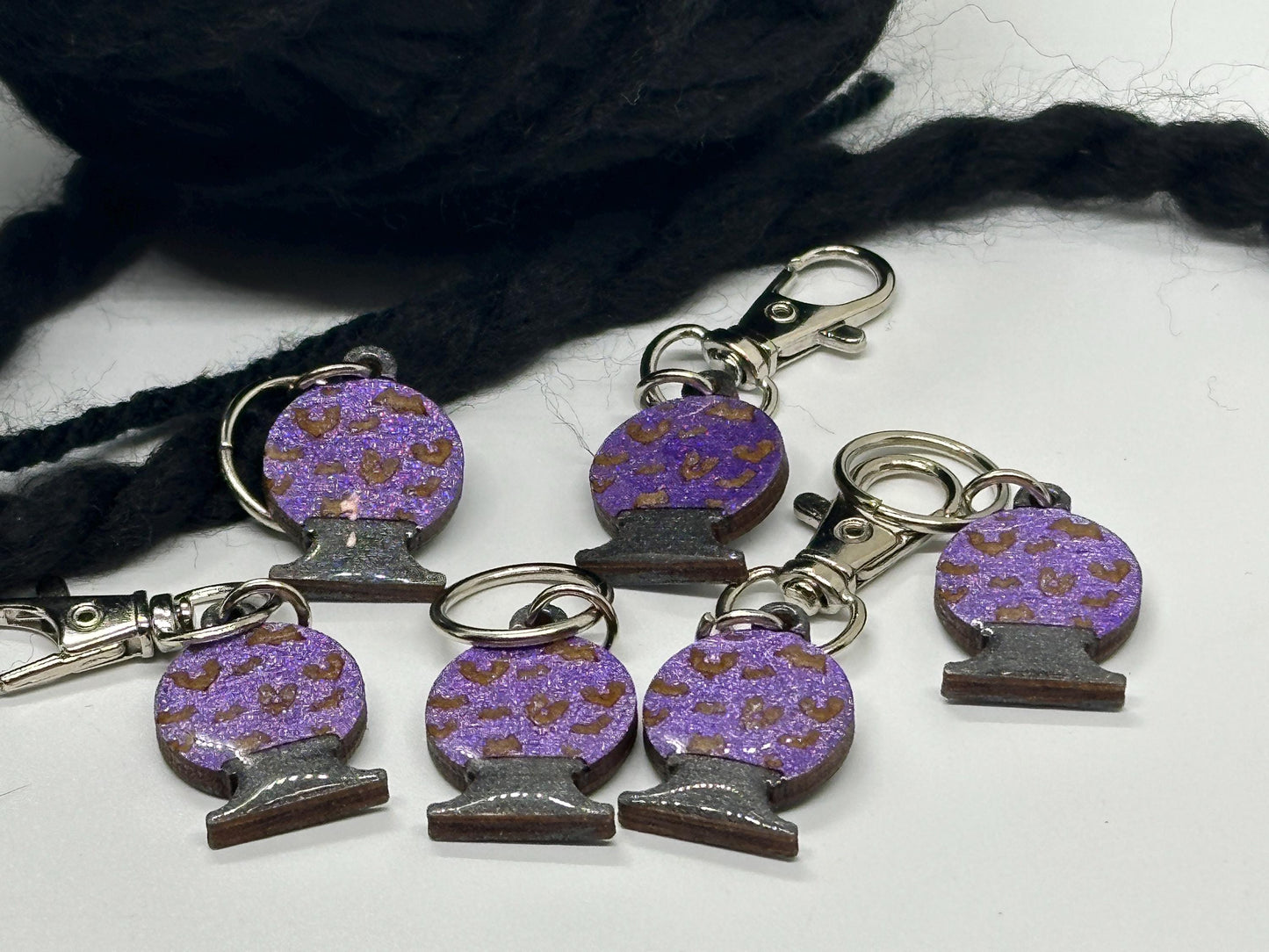 Purple and brown keychain charms on a white surface with black yarn.