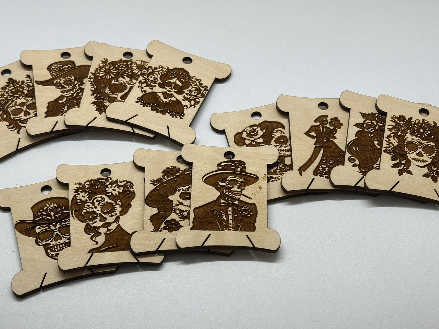 Wooden bobbins with laser-cut designs of faces on a white background