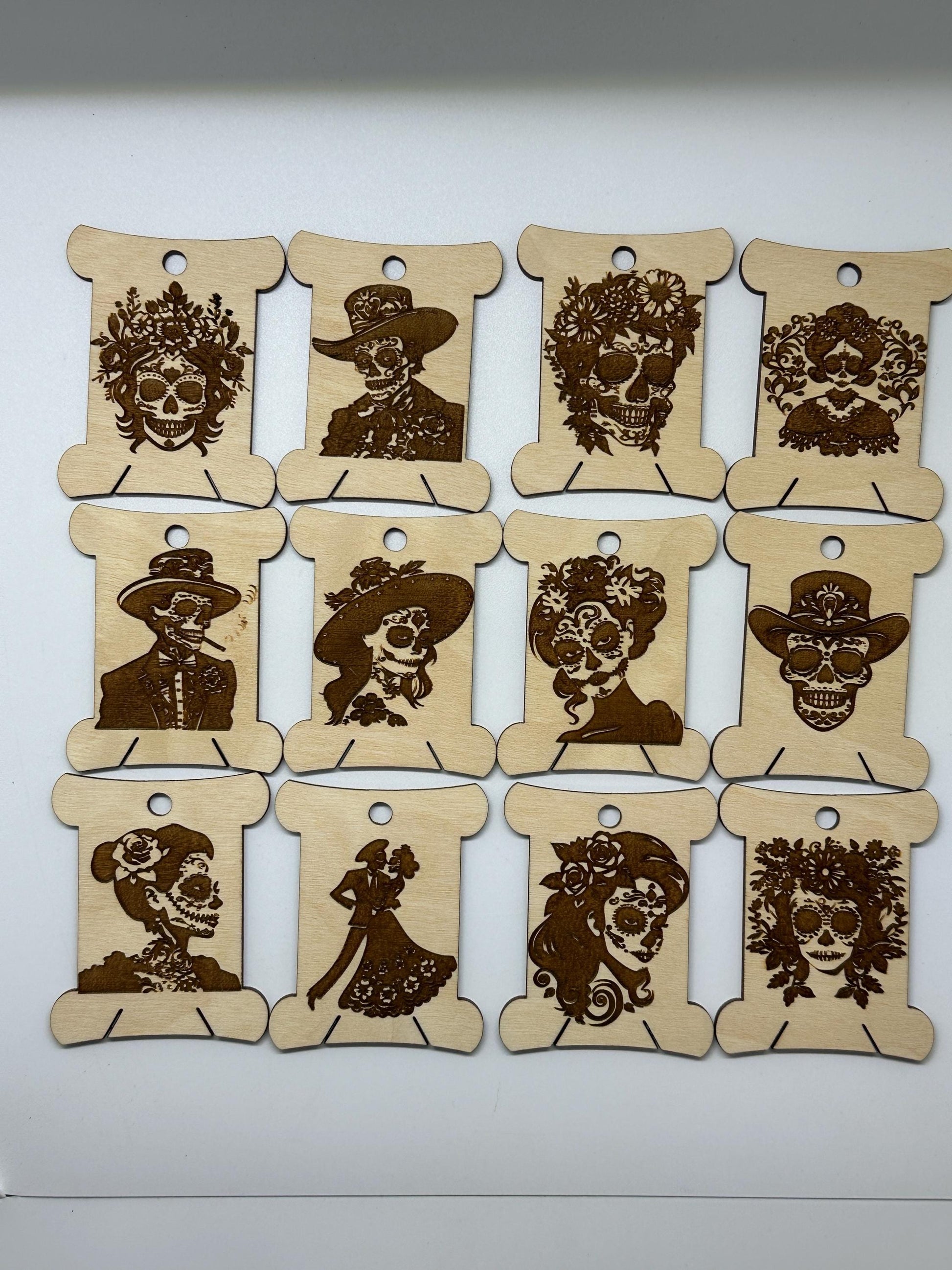 Nine wooden bobbins  with laser-cut decorative skull designs on a white background