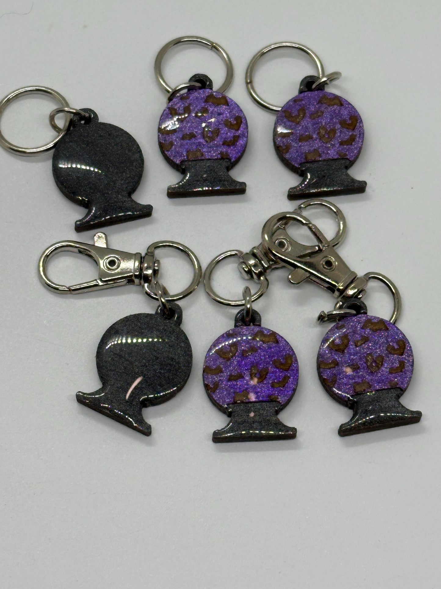 Set of keychains with purple and black designs on a white background