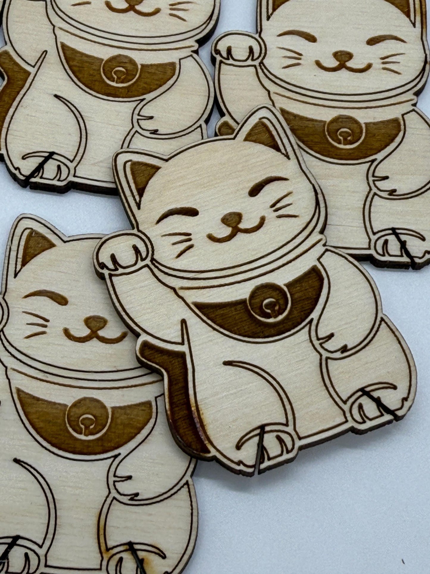 Wooden cutouts of cartoonish cat characters with one raised paw on a white background