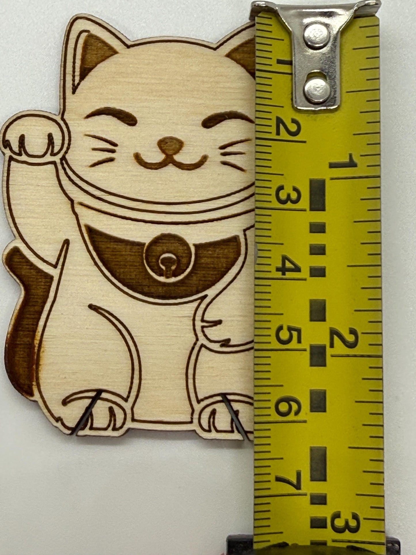 Wooden cat bobbin with a measuring tape for scale on a white background