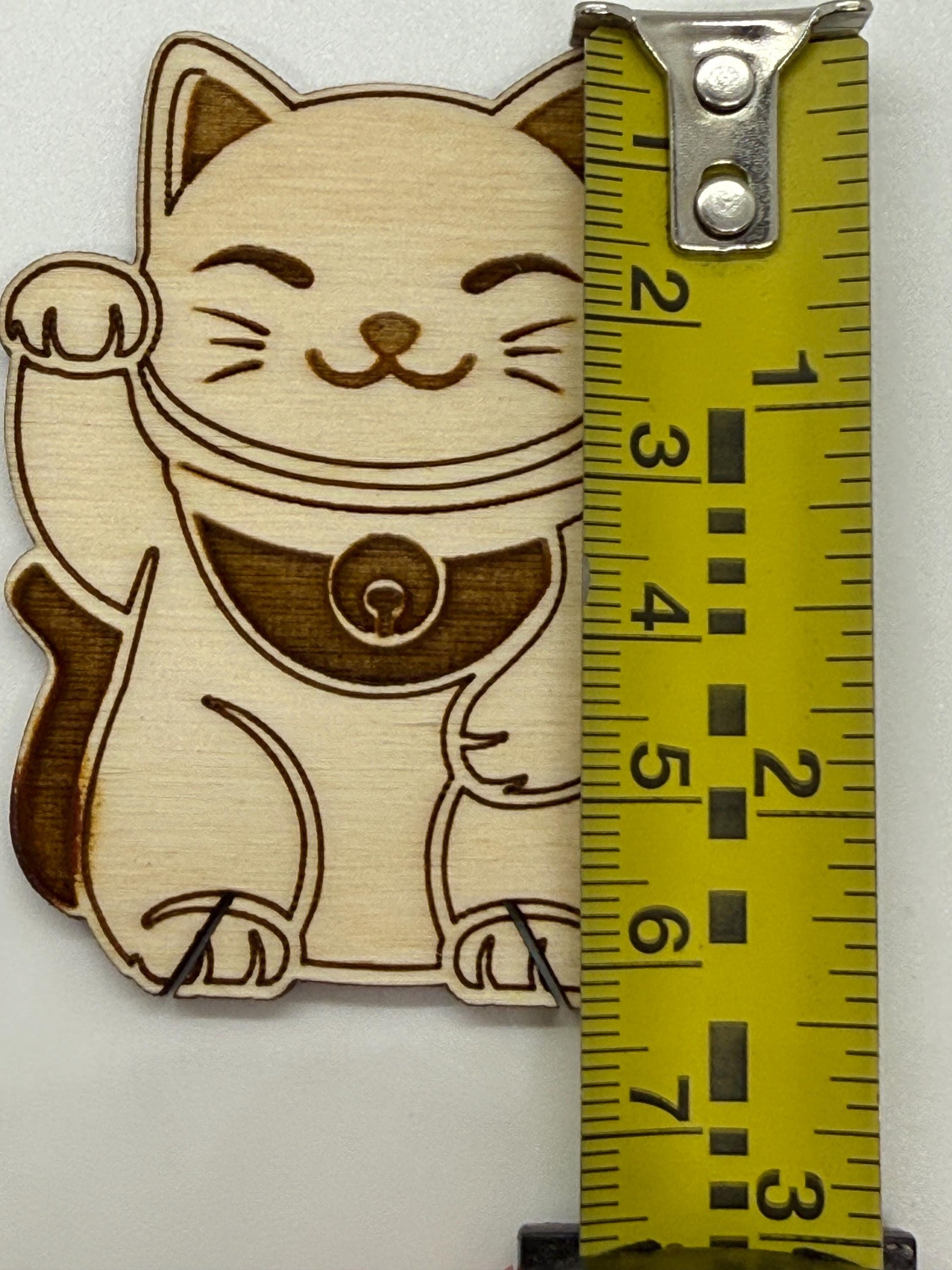 Wooden cat bobbin with a measuring tape for scale on a white background