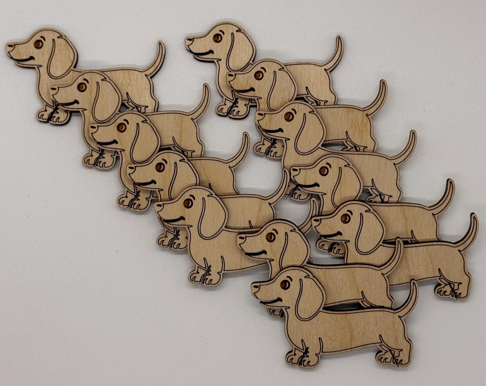Wooden cutouts of dachshunds arranged in a pattern on a white background
